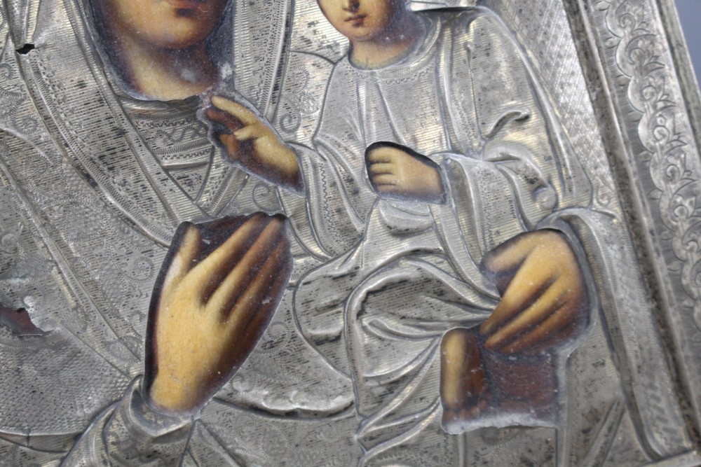 A Russian white metal overlaid tempera on panel icon, depicting the Virgin Mary and Christ child, 22 x 18cm